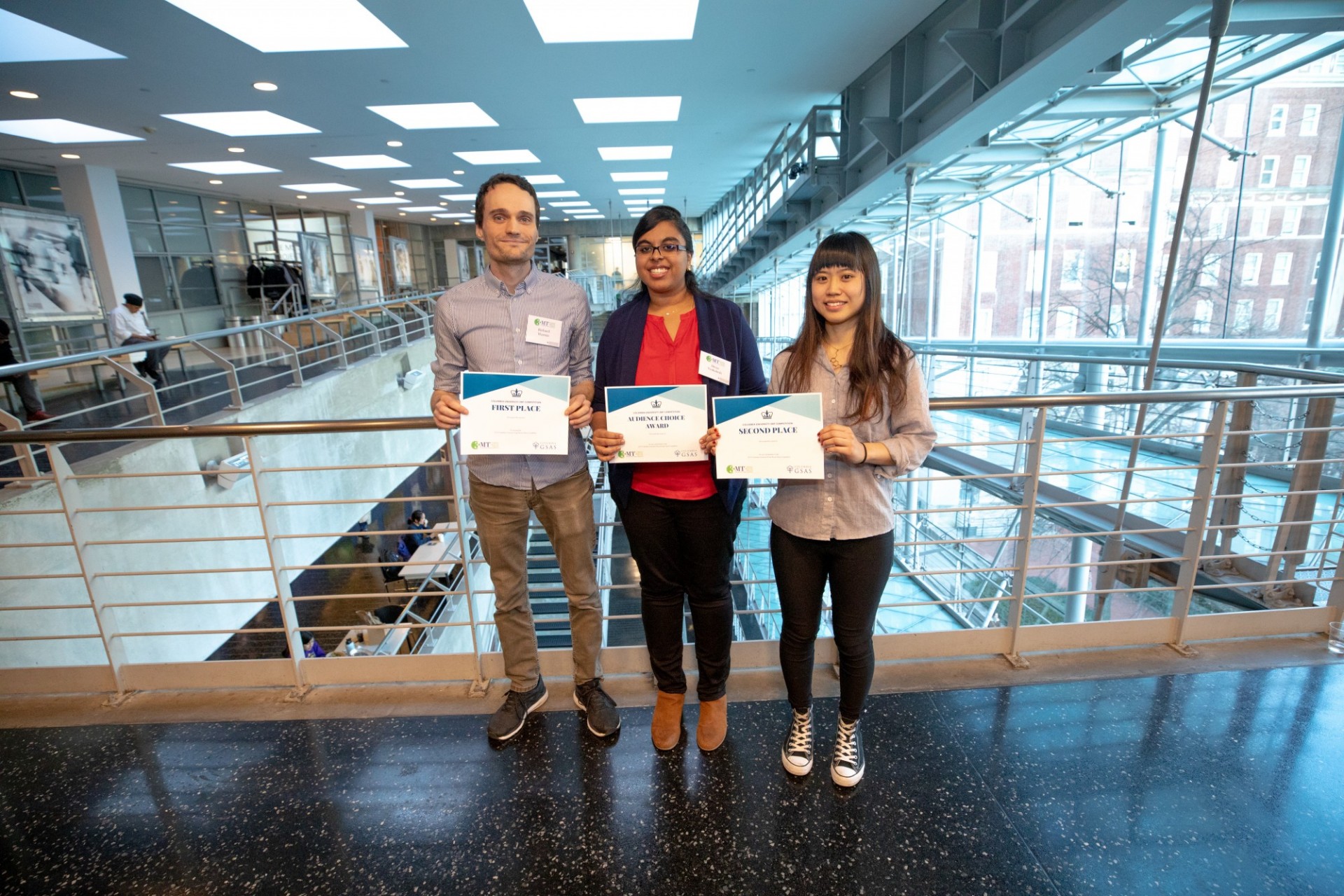 three students holding award certificates