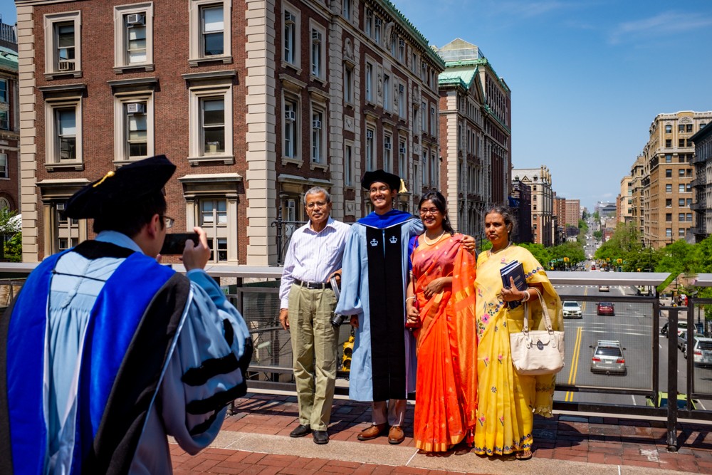 A proud graduate poses for a photo with his family at Ancel Plaza above Amsterdam Avenue.